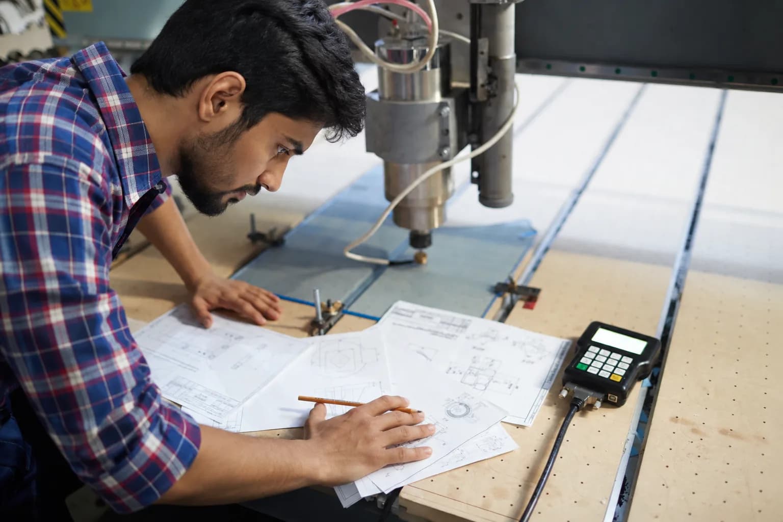 An engineer marking up technical drawings at a machine table
